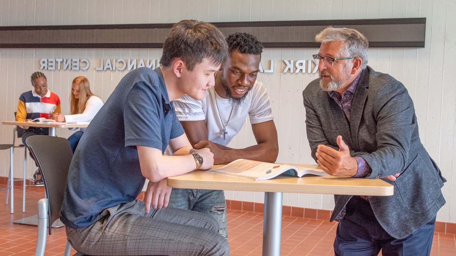 Two business students having a discussion with a professor